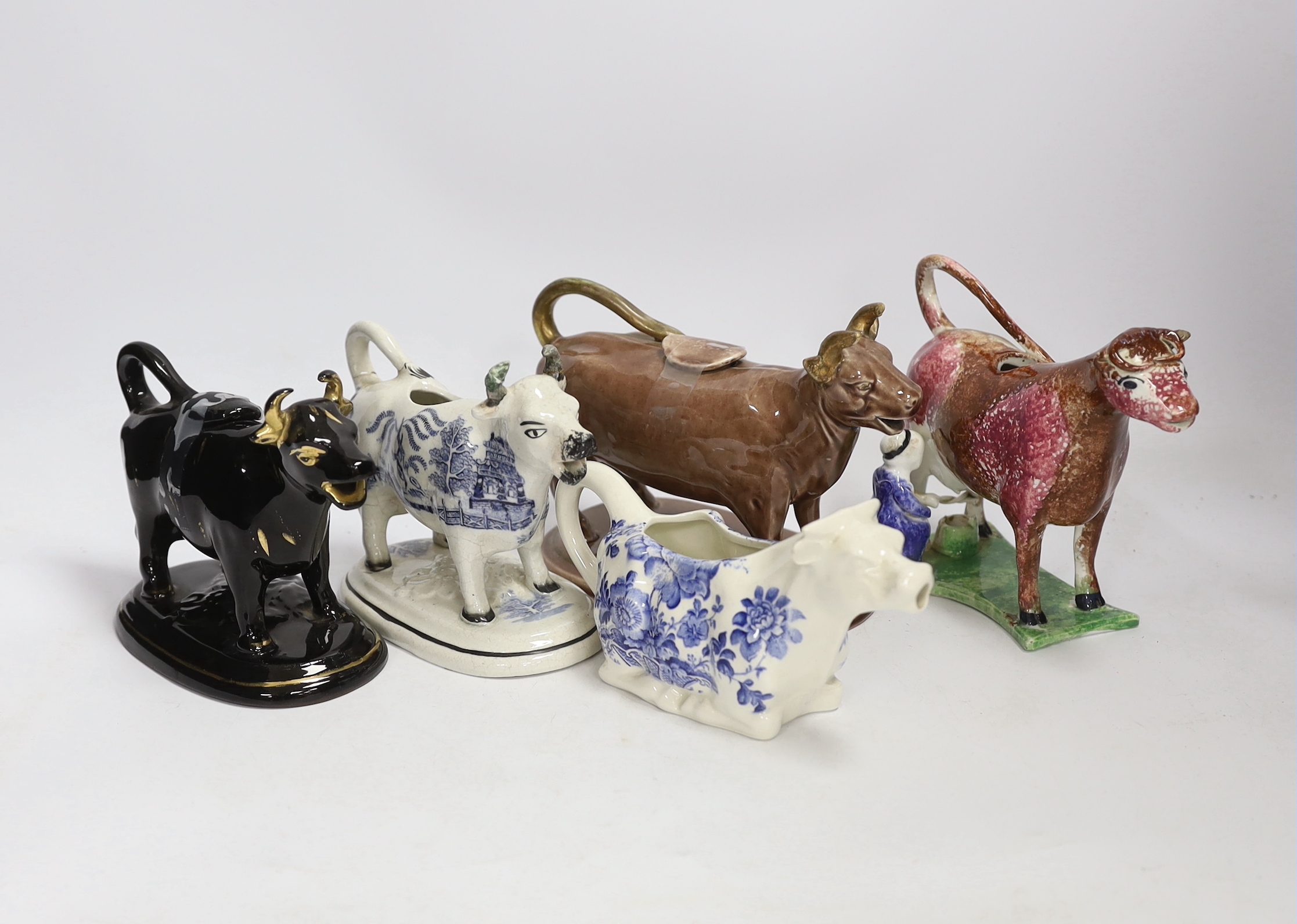 Five 19th century and later pottery cow creamers, including an early 19th century pearlware sponged creamer modelled with the seated figure of a milk maid tallest 13cm